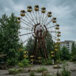 Ciudad fantasma de Pripyat con la noria abandonada y vegetación creciendo entre edificios.